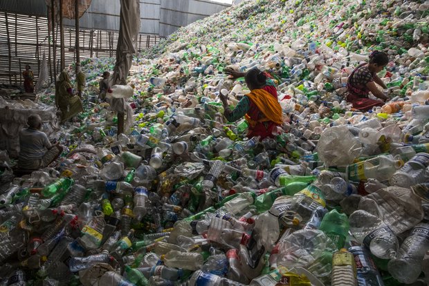 Menschen arbeiten in einem riesigen Haufen Plastikflaschen.