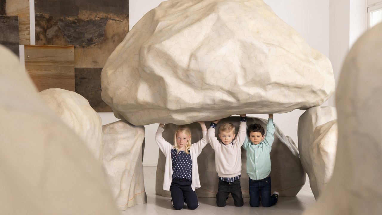 Drei Kinder entdecken das nachgebaute Großsteingrab in der Geest Ausstellung.